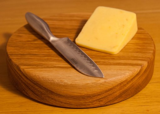 Solid oak cheese board with cheese placed on top.